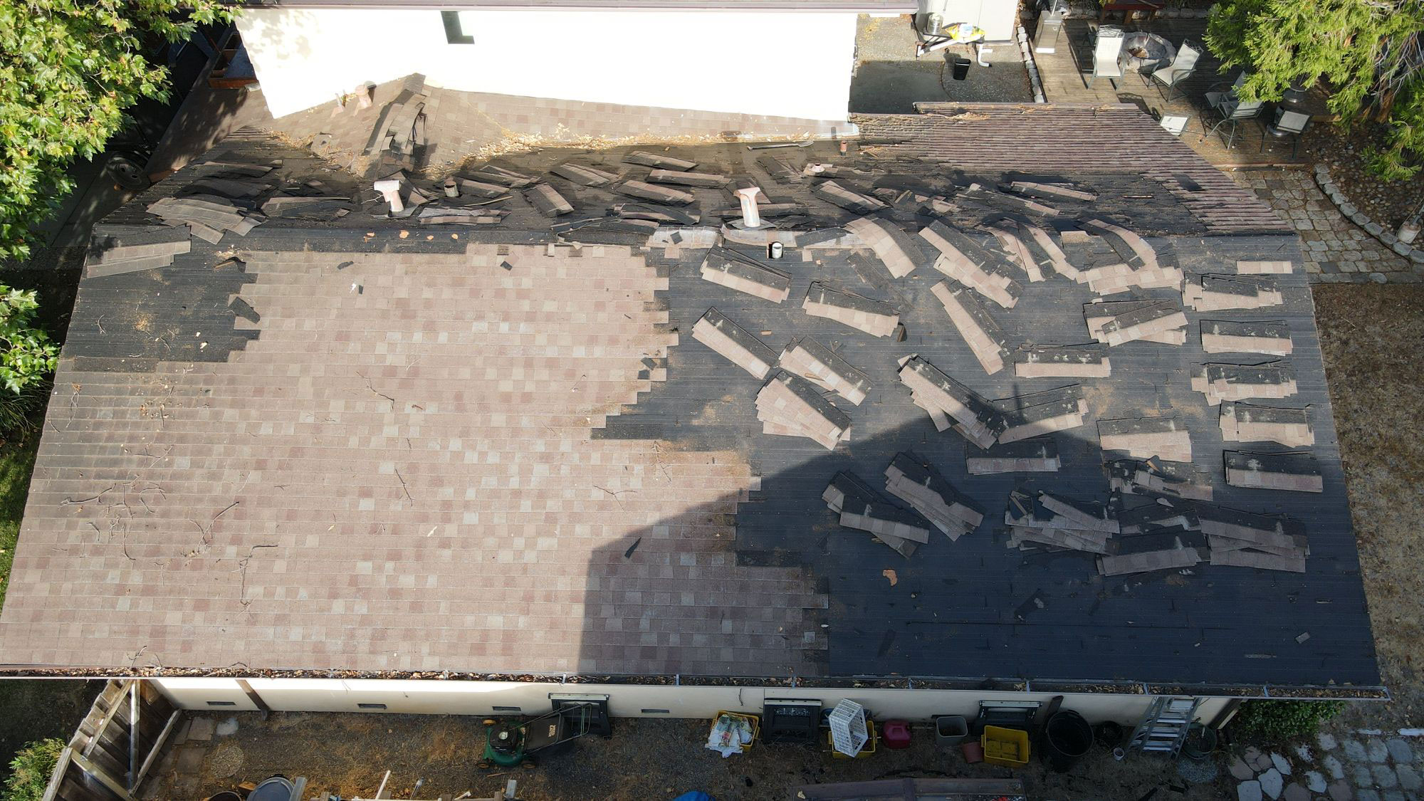 The image shows a building with a damaged roof, where some of the shingles have been removed, revealing the underlying structure.