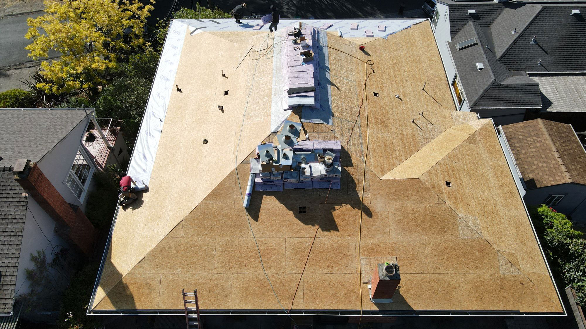 The image shows a large, flat roof under construction with visible wooden studs and insulation materials, suggesting ongoing renovation work.