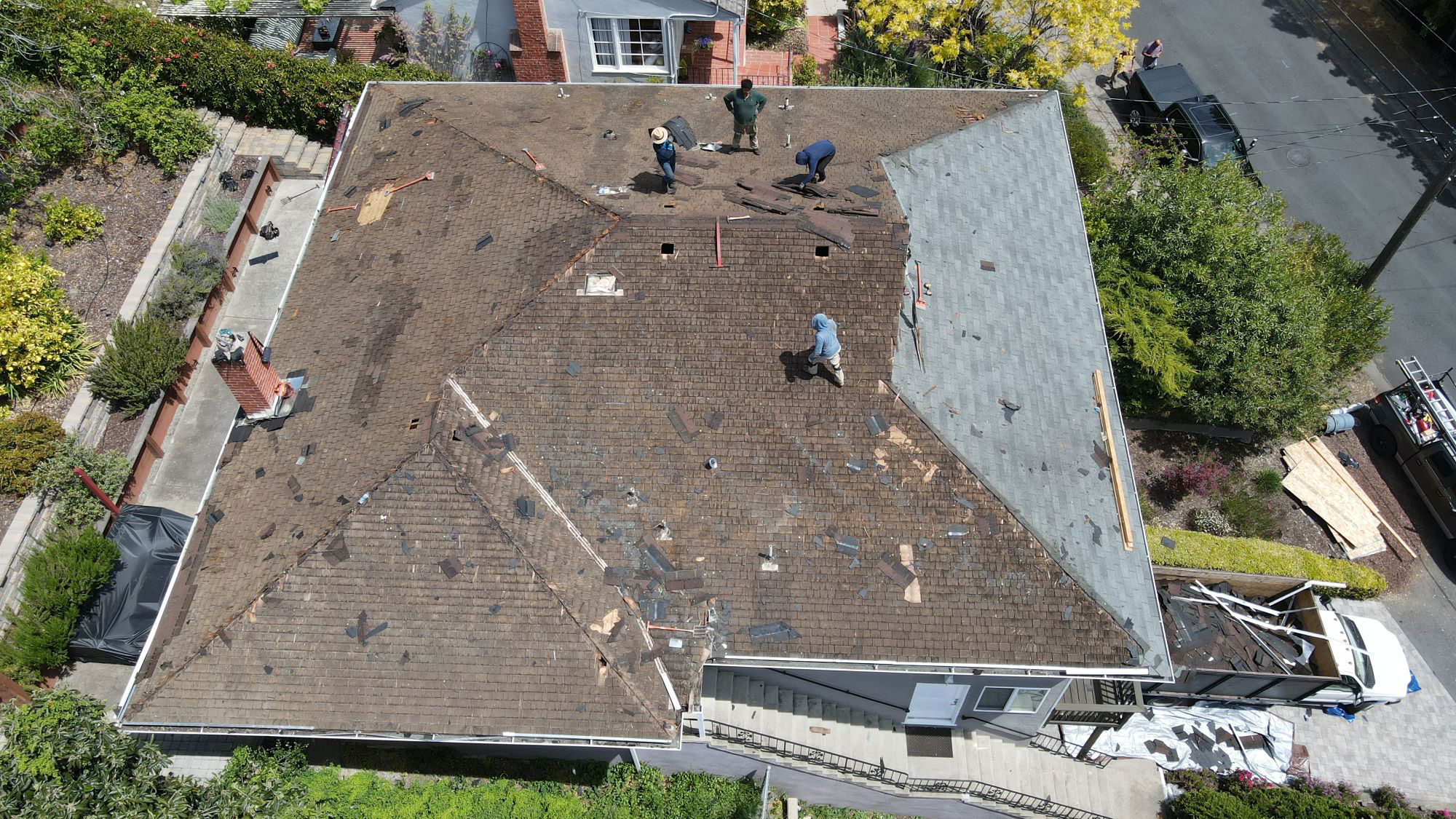 The image shows a roof under construction or repair with workers on site, indicating ongoing maintenance or renovation work.