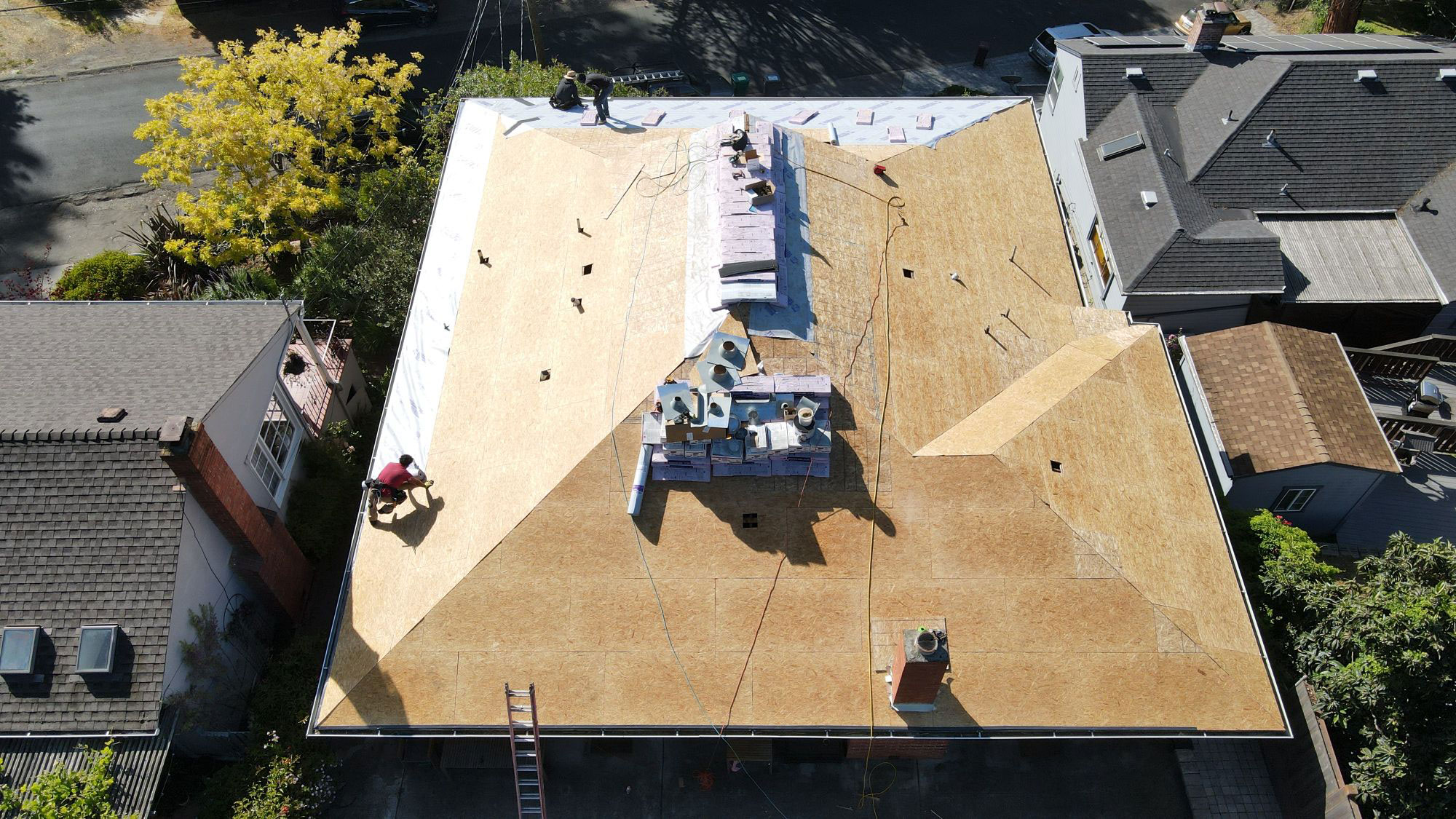 The image shows a roof under construction with workers onsite, using aerial perspective for accessibility purposes.
