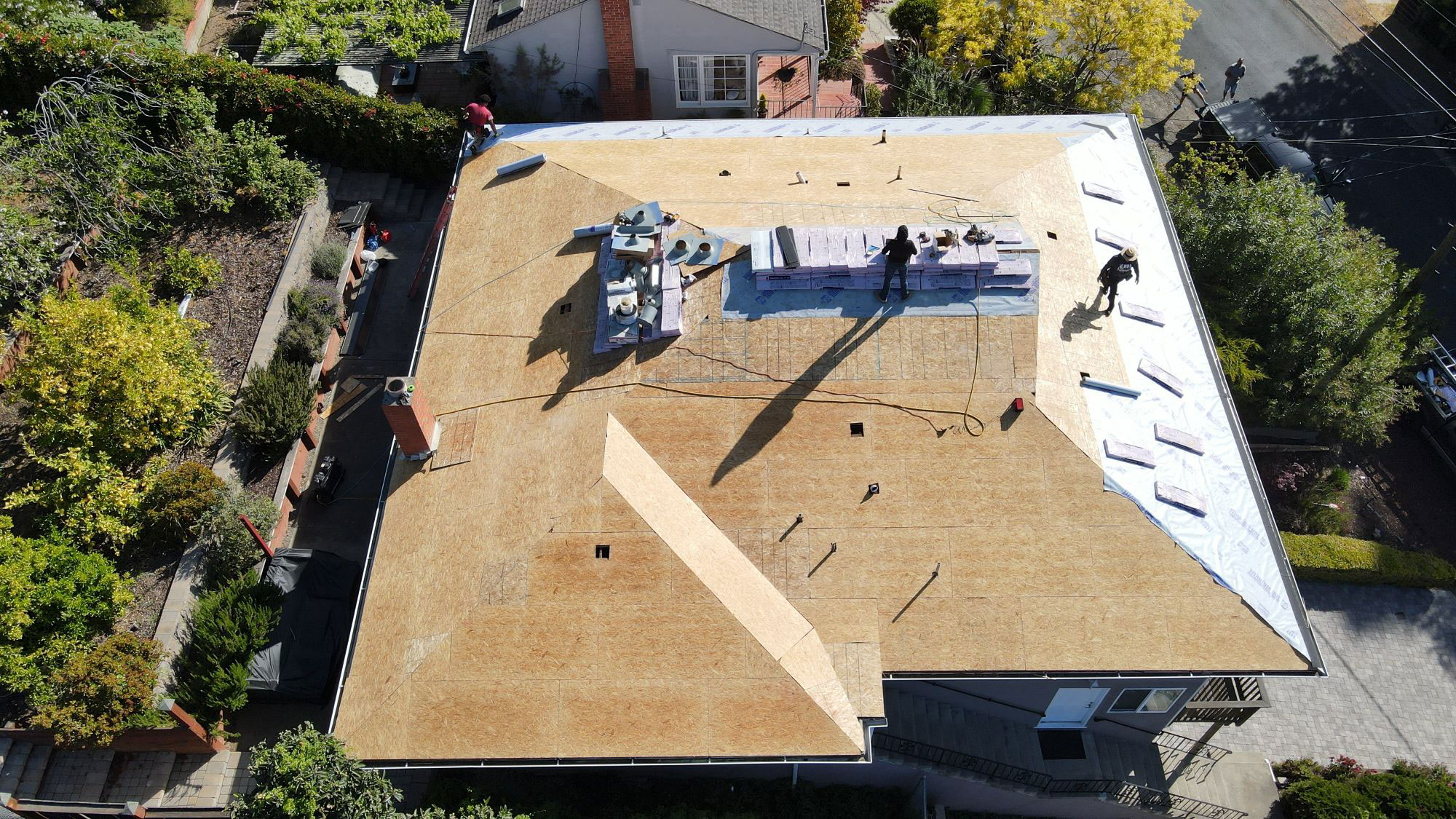 The image depicts a building under construction with visible roofing materials and workers on site.