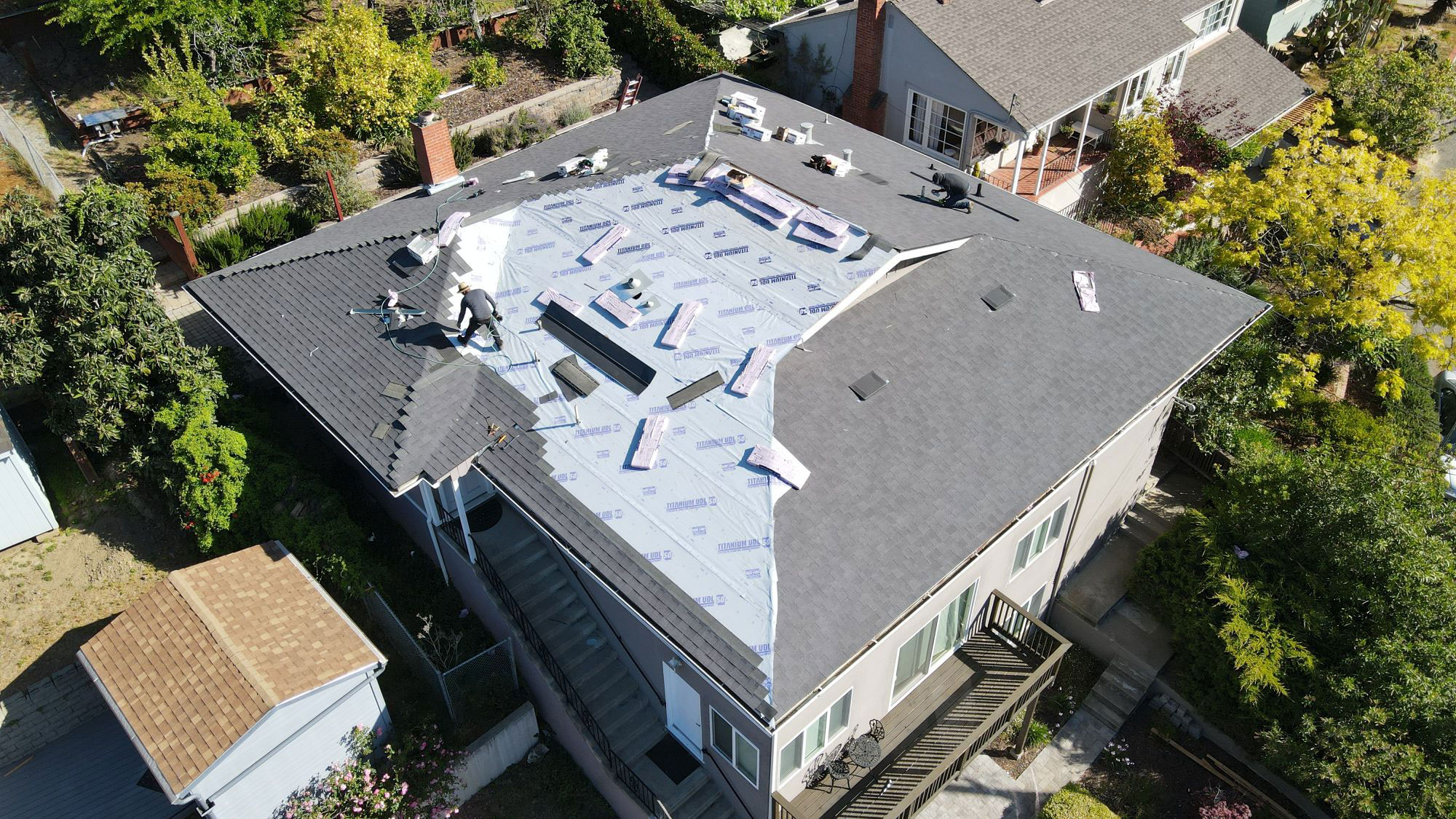 The image shows a residential property undergoing roof renovation with construction materials visible on the roof.