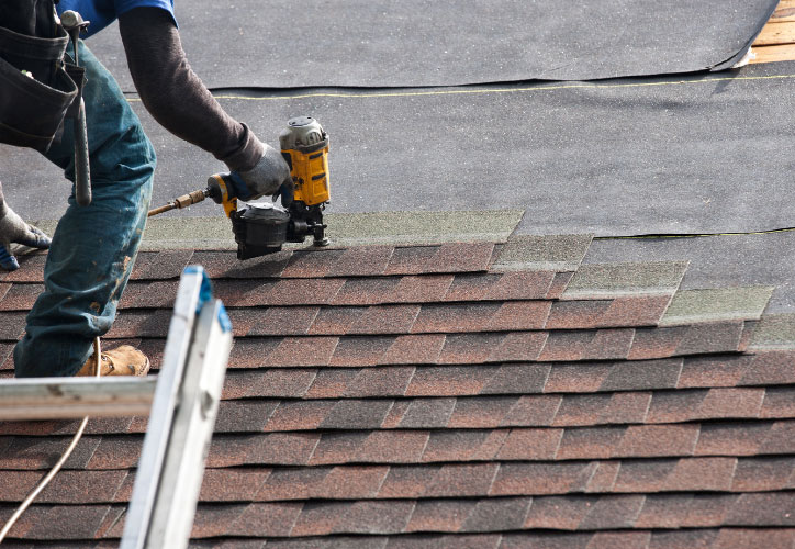 A construction worker using a power tool on a roof under repair.