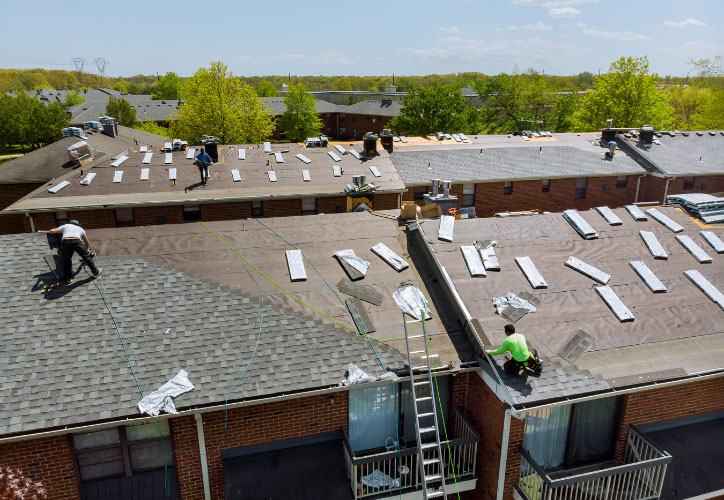 The image shows a residential building with a sloped roof undergoing construction or renovation work, featuring solar panels installed on its surface.